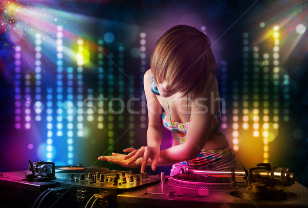 Dj girl playing songs in a disco with light show Stock photo © ra2studio