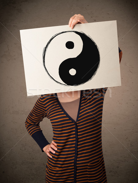 Woman holding a paper with a yin-yang on it in front of her head Stock photo © ra2studio