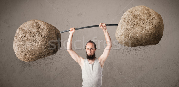 skinny guy lifting large rock stone weights Stock photo © ra2studio