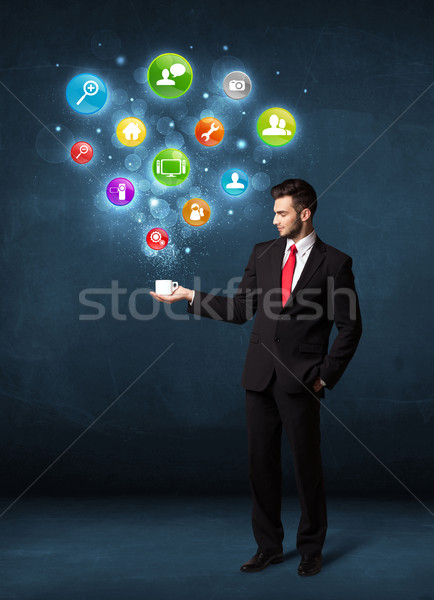 Businessman holding a white cup with setting icons Stock photo © ra2studio