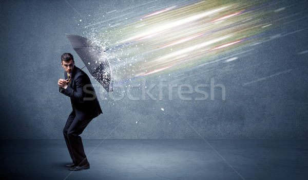 Business man defending light beams with umbrella concept Stock photo © ra2studio