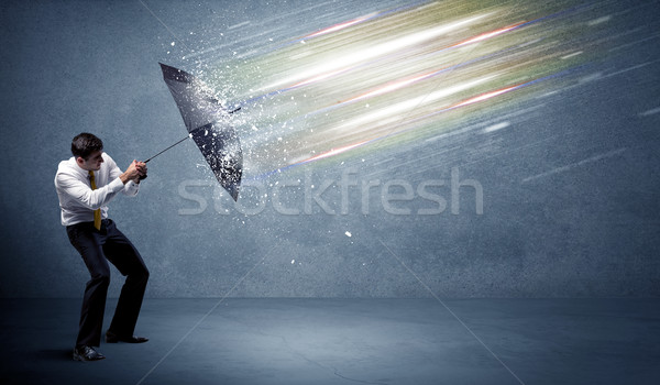 Business man defending light beams with umbrella concept Stock photo © ra2studio