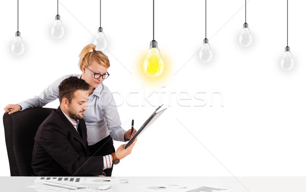 Business man and woman sitting at table with idea light bulbs Stock photo © ra2studio