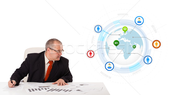 businessman sitting at desk with a globe and social icons Stock photo © ra2studio