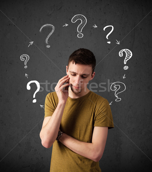 Stock photo: Thoughtful young man with drawn question marks circulating around his head