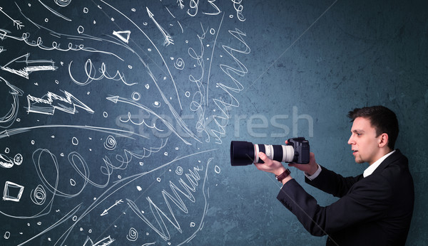 Photographer boy shooting images while energetic hand drawn lines and doodles come out of the camera Stock photo © ra2studio