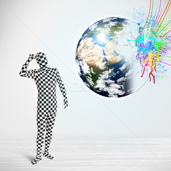 Funny man in body suit looking at colorful splatter earth Stock photo © ra2studio