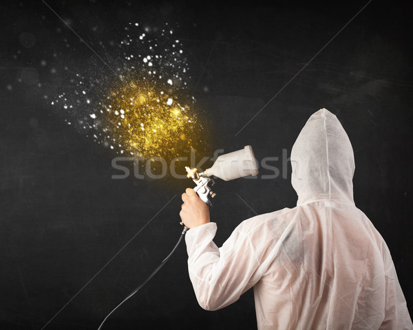 Worker with airbrush painting with glowing golden paint  Stock photo © ra2studio