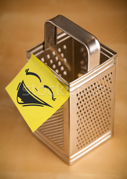 Stock photo: Post-it note with smiley face sticked on grater