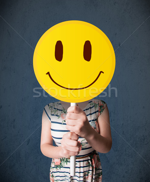Fiatal nő tart mosolygós arc emotikon fiatal hölgy Stock fotó © ra2studio