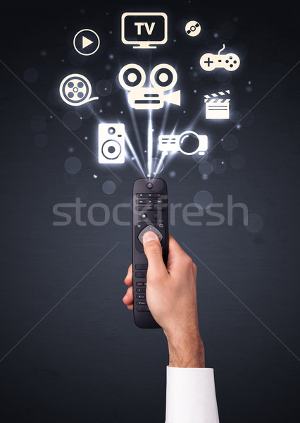 Hand with remote control and media icons Stock photo © ra2studio