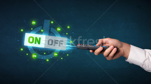 Hand with remote control and on-off signals Stock photo © ra2studio