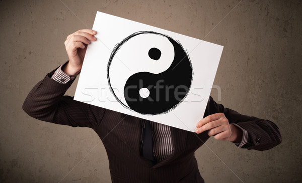 Businessman holding a paper with a yin-yang on it in front of hi Stock photo © ra2studio