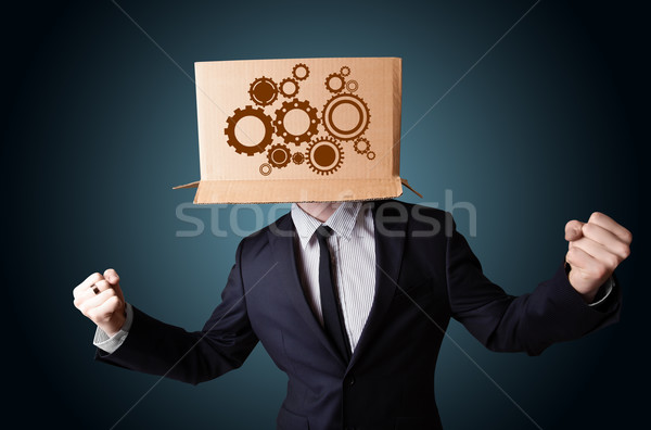 Businessman gesturing with a cardboard box on his head with spur Stock photo © ra2studio