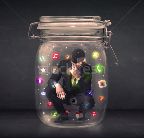 Businessman captured in a glass jar with colourful app icons con Stock photo © ra2studio