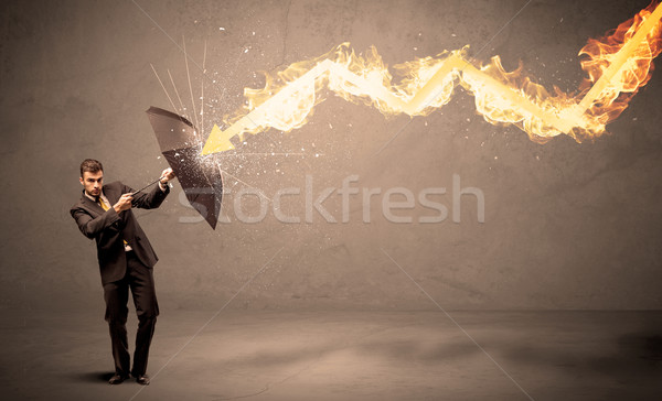 Stock photo: Business man defending himself from a fire arrow with an umbrell