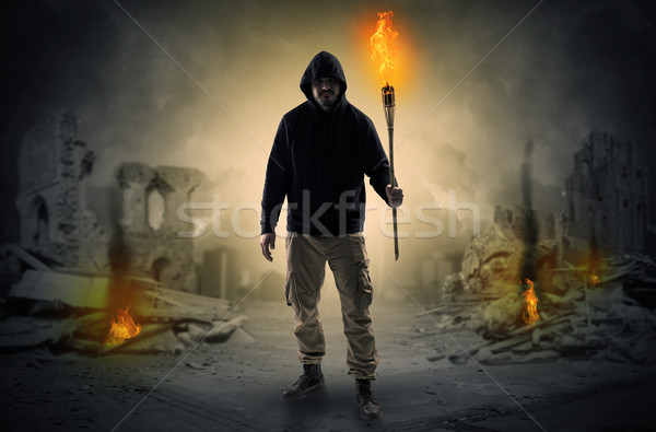 Man coming with burning flambeau at a catastrophe scene concept Stock photo © ra2studio
