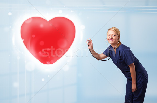 Stock photo: Young nurse healing a red heart