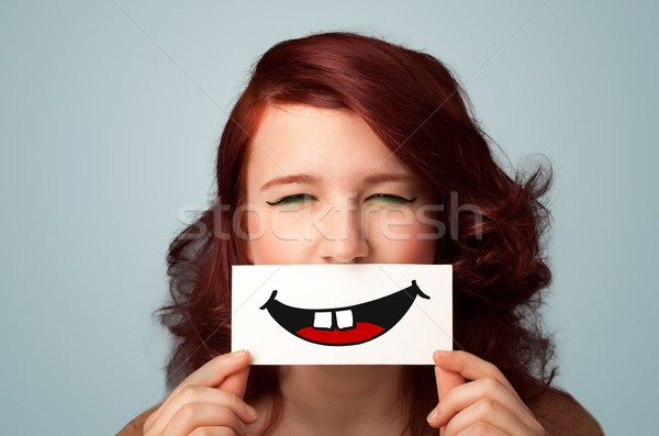 Happy pretty woman holding card with funny smiley Stock photo © ra2studio