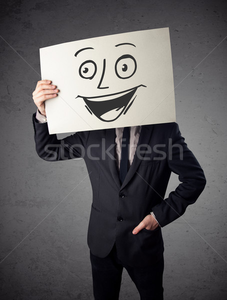 Businessman holding a cardboard with smiley face on it in front  Stock photo © ra2studio