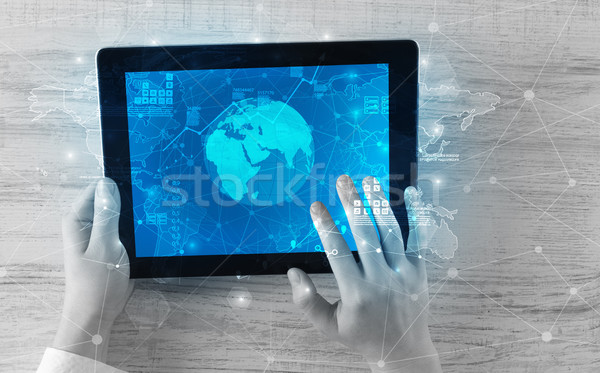 Hand holding tablet with global reports and stock market change  Stock photo © ra2studio