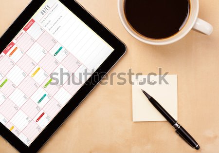 Stock photo: Tablet pc with empty space and a cup of coffee on a desk