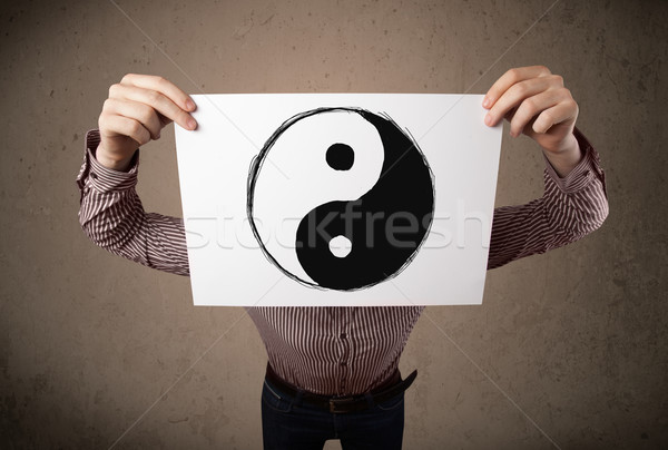 Businessman holding a paper with a yin-yang on it in front of hi Stock photo © ra2studio