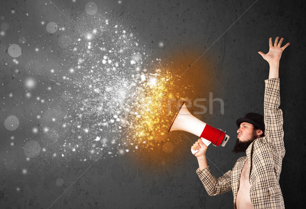 Guy shouting into megaphone and glowing energy particles explode Stock photo © ra2studio