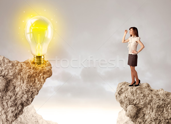 Businesswoman on rock mountain with idea bulb Stock photo © ra2studio