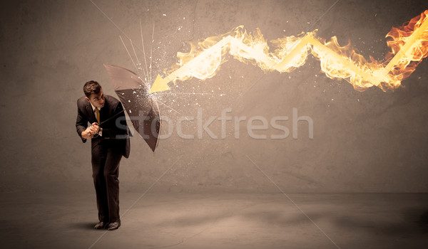 Stock photo: Business man defending himself from a fire arrow with an umbrell