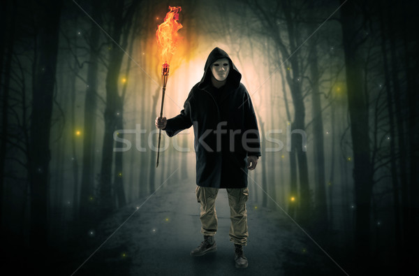 Stock photo: Man coming from dark forest with burning flambeau in his hand concept