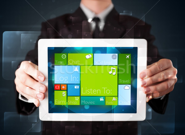 Stock photo: Young businessman holding a tablet with modern software operational system