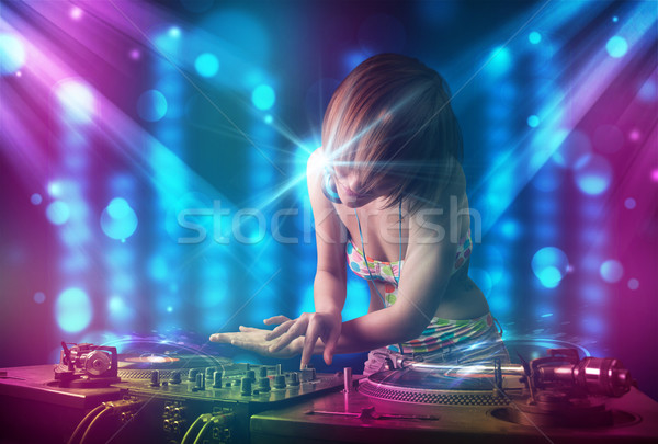 Dj girl mixing music in a club with blue and purple lights Stock photo © ra2studio