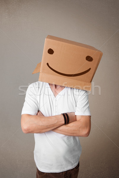 Young man gesturing with a cardboard box on his head with smiley Stock photo © ra2studio