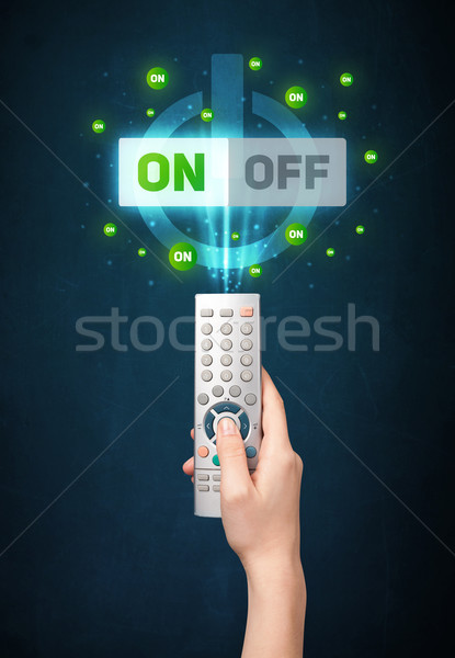 Hand with remote control and on-off signals Stock photo © ra2studio