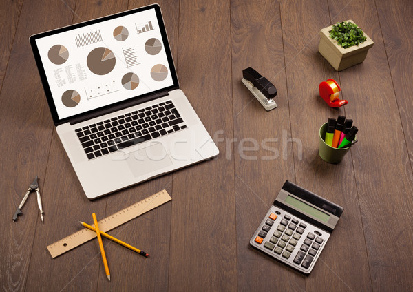 Stock photo: Pie chart graph icons on laptop screen with office accessories 