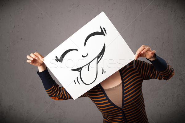 Woman holding a paper with cute smiley face on it in front of he Stock photo © ra2studio