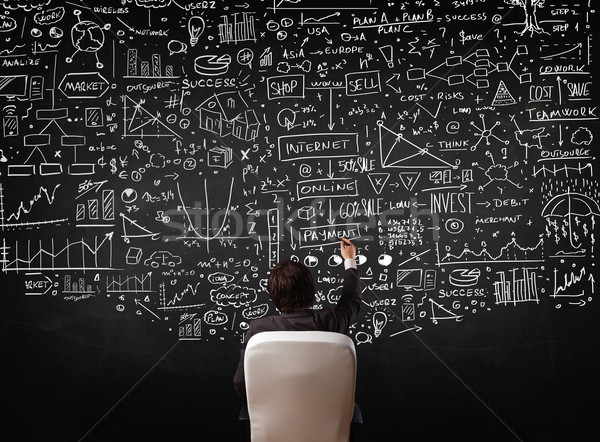 Businessman sitting in front of a blackboard with charts Stock photo © ra2studio