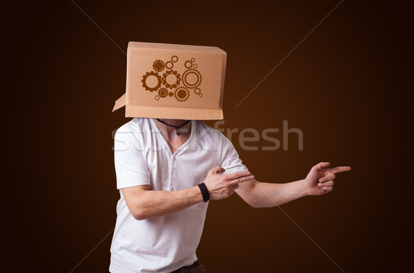 Young man gesturing with a cardboard box on his head with spur w Stock photo © ra2studio