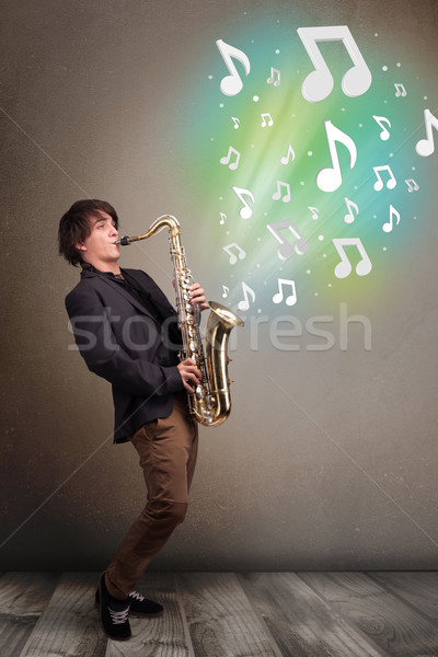 Young musician playing on saxophone while musical notes explodin Stock photo © ra2studio