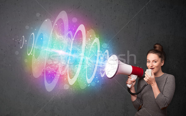 Young girl yells into a loudspeaker and colorful energy beam com Stock photo © ra2studio