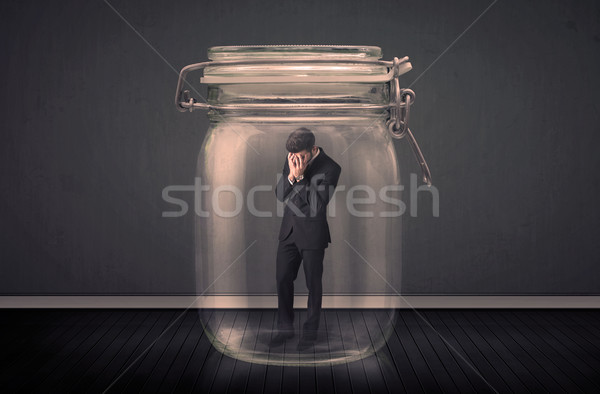 Stock photo: Businessman trapped into a glass jar concept
