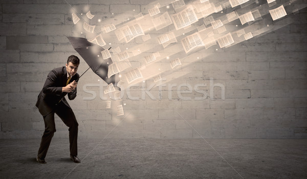 Business man protecting with umbrella against wind of papers Stock photo © ra2studio