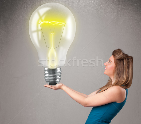 Beautiful lady holding realistic 3d light bulb Stock photo © ra2studio