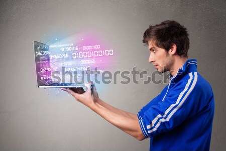 Casual man holding laptop with exploding data and numbers Stock photo © ra2studio