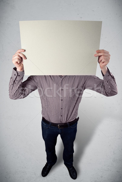 Stock photo: Businessman holding in front of his head a paper with copy space