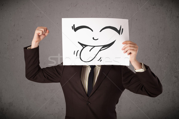Businessman holding a paper with funny smiley face in front of h Stock photo © ra2studio