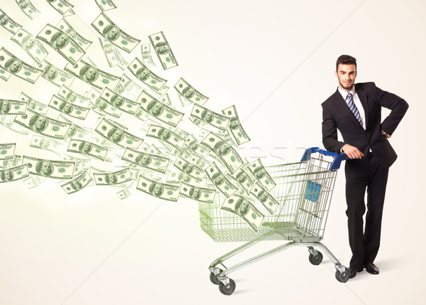 Businessman with shopping cart with dollar bills Stock photo © ra2studio