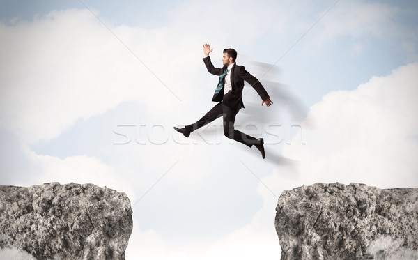 Divertente uomo d'affari jumping rocce gap business Foto d'archivio © ra2studio