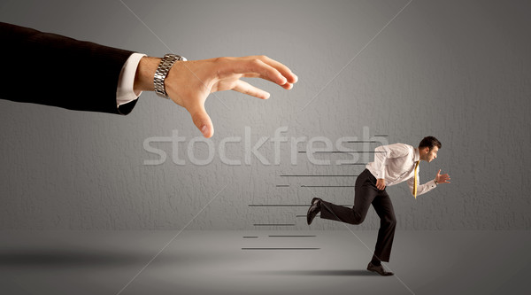 Businessman running away from a huge hand Stock photo © ra2studio